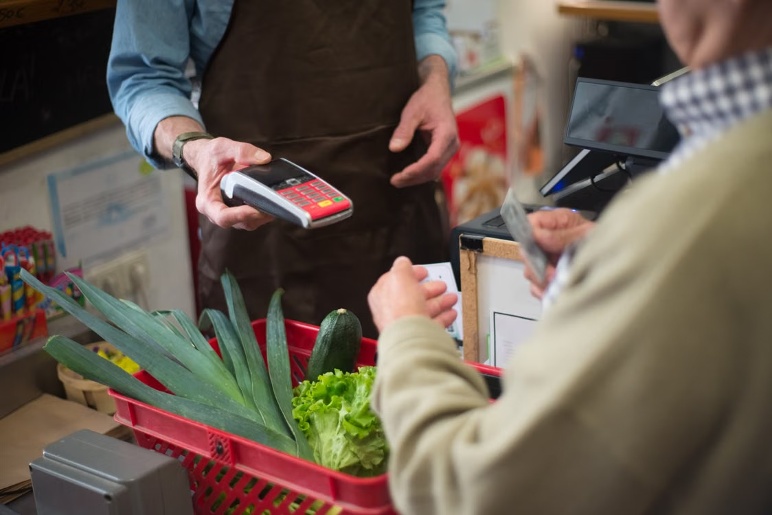 Chủ cửa hàng bán lẻ thanh toán cho khách bằng máy POS